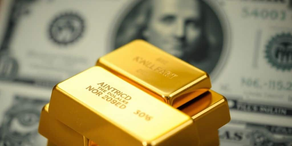 Barres d'or brillantes avec un dollar en arrière-plan.
