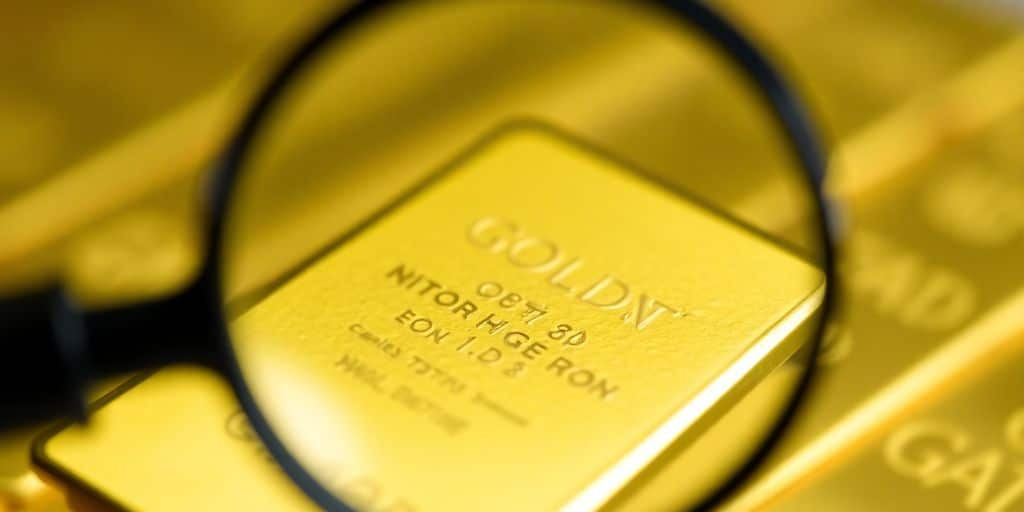 Gros plan sur un lingot d'or avec une loupe.