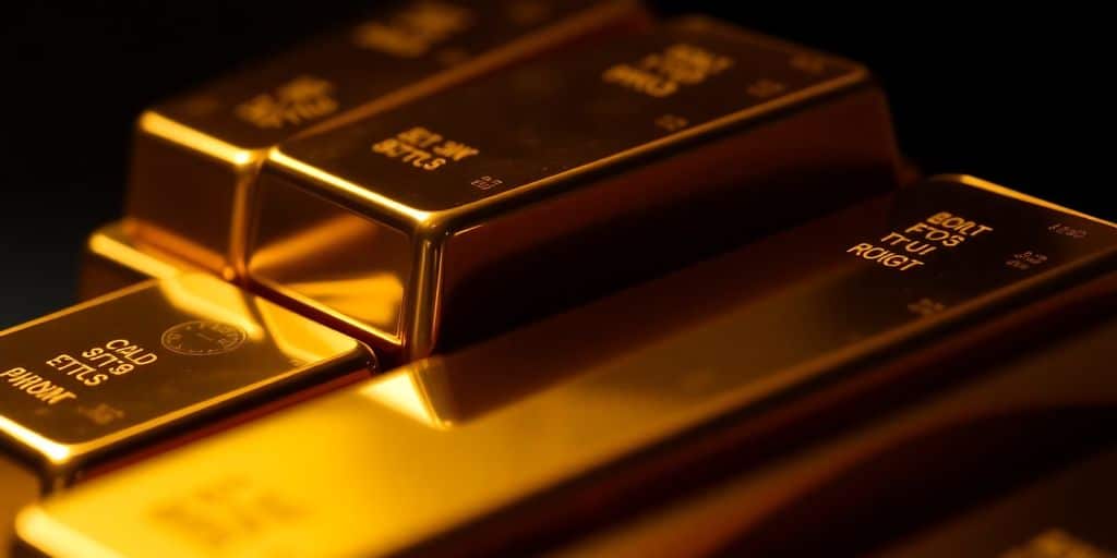 Des barres d'or empilées sur un fond sombre.