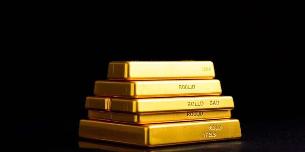 Des barres d'or empilées sur un fond sombre.