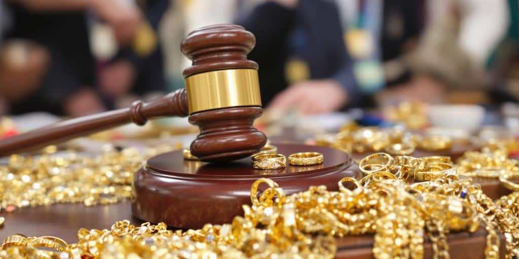 Bijoux en or près d’un marteau de commissaire-priseur