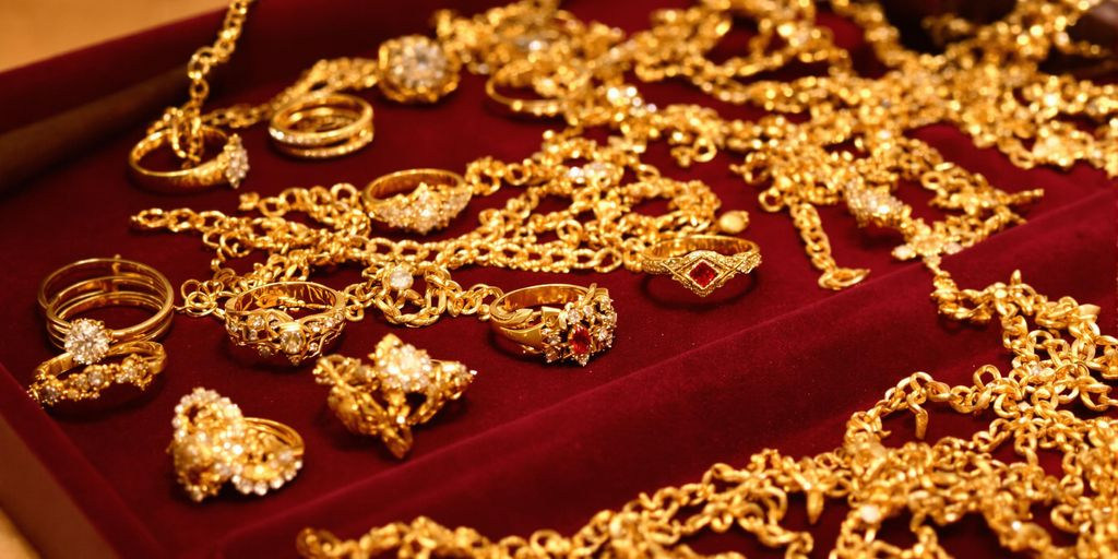 Bijoux en or et marteau de commissaire-priseur sur plateau.