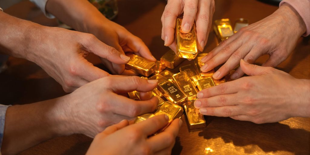 Mains de famille partageant des lingots d'or sur une table.