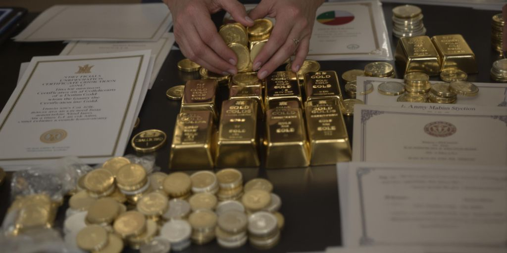 Lingots d’or, pièces et documents officiels sur une table.