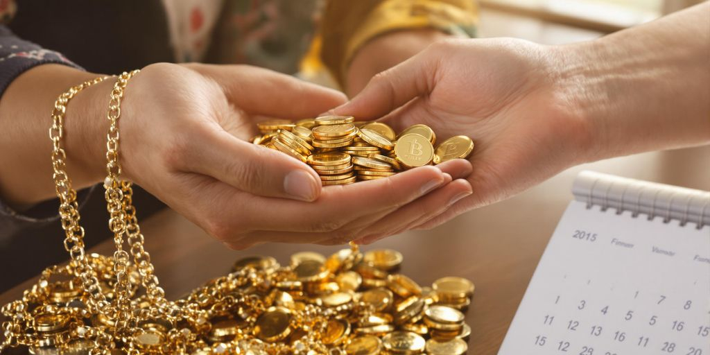 Main tenant des pièces et bijoux en or devant un calendrier