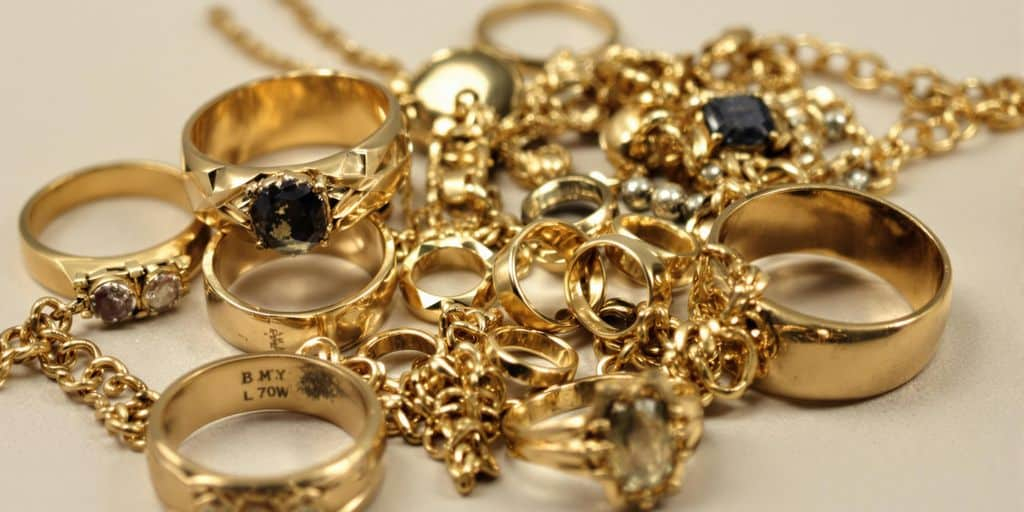 Bijoux en or abîmés posés sur une surface claire.