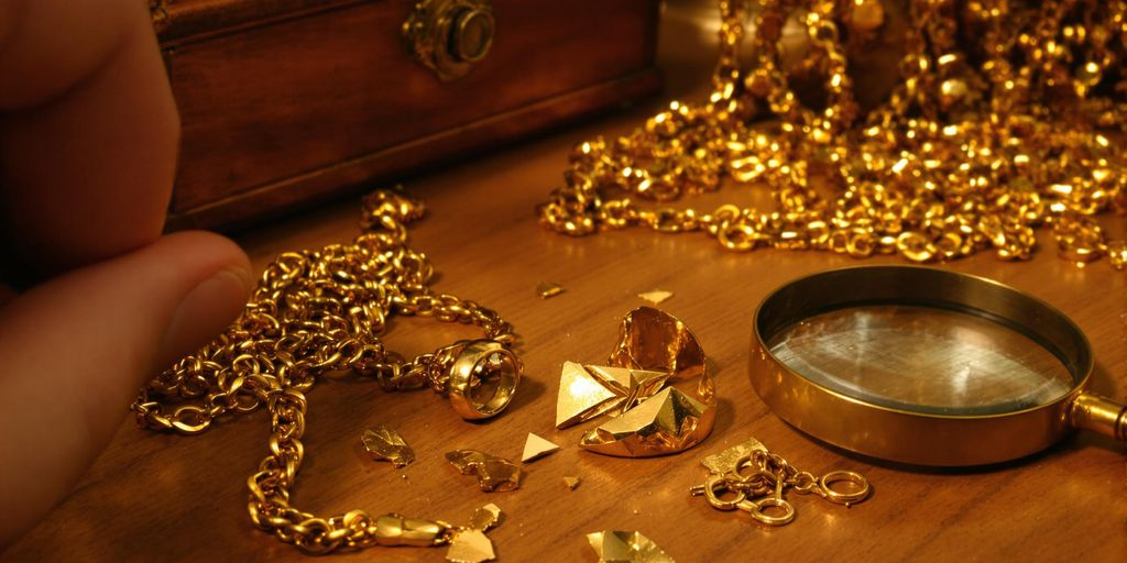 Bijoux cassés sur une table avec une main et loupe