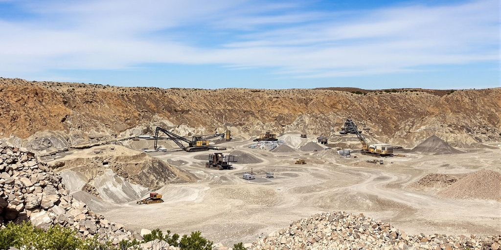 Panorama d'un vaste site minier, machines usées, sols argentés naturels.