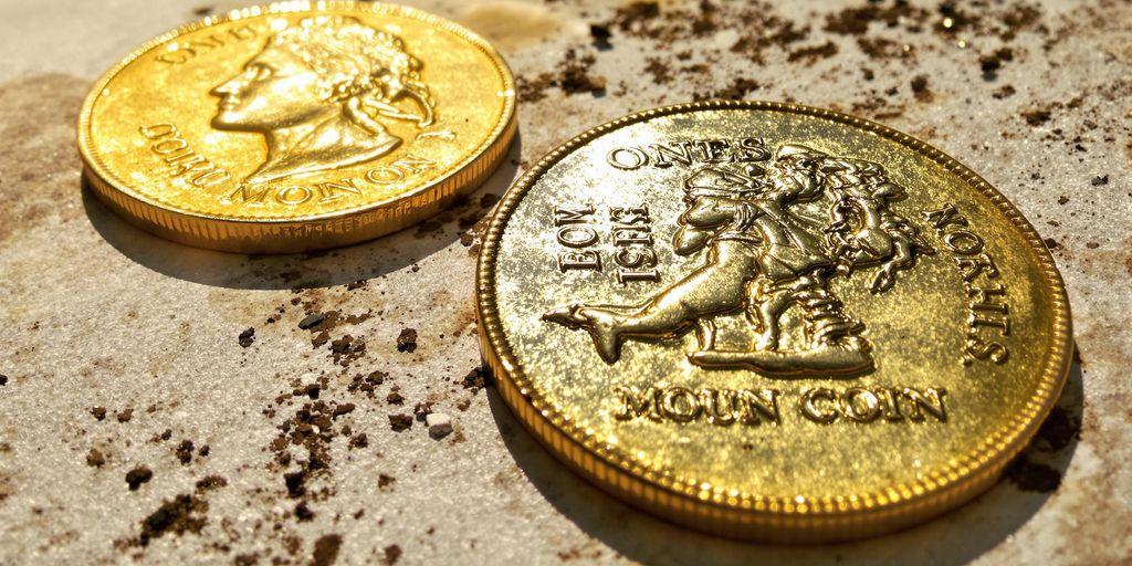 Pièces d’or et d’argent posées sur une surface vieillie, lumineuse.