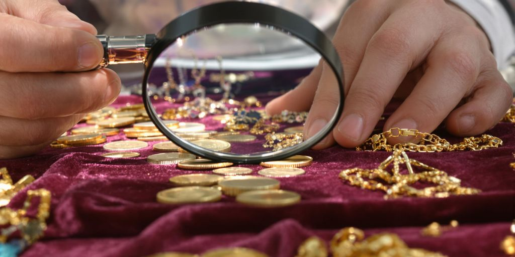 Bijoutier expert inspectant des bijoux en or sur une table.