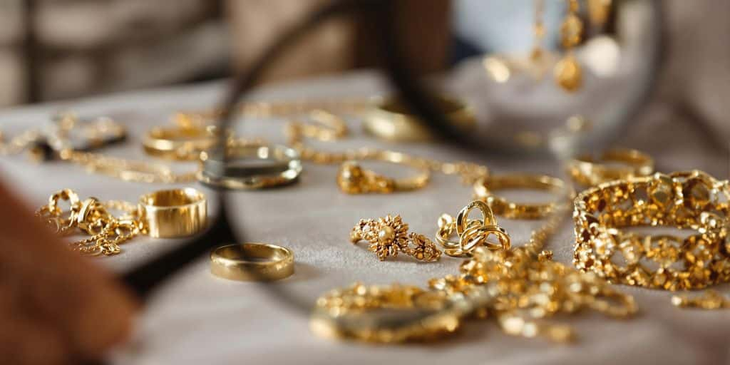 Bijoux en or sur velours avec loupe d'examen en arrière-plan.