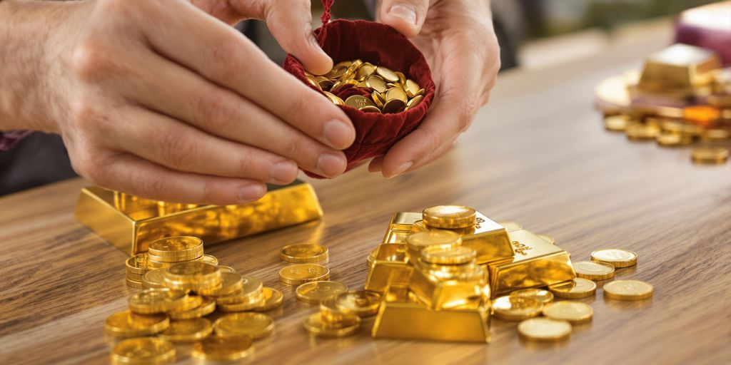 Deux mains échangent des pièces et lingots d'or brillants.