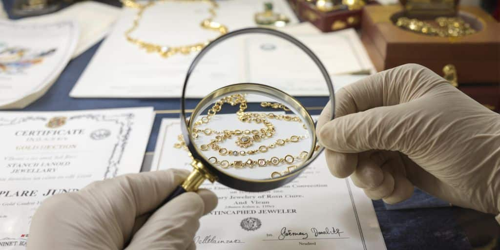 Bijoux en or anciens examinés par un expert aux enchères.