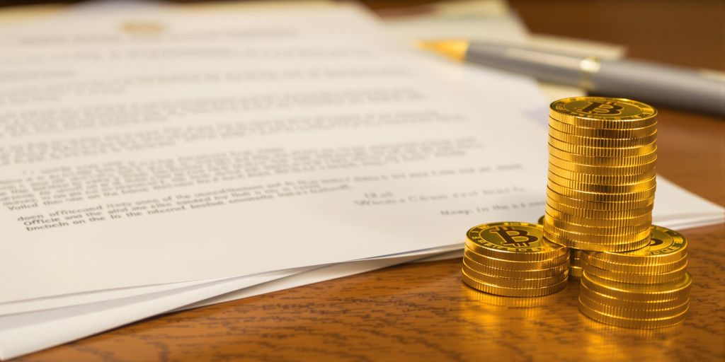 Pièces d’or empilées et documents papier côte à côte