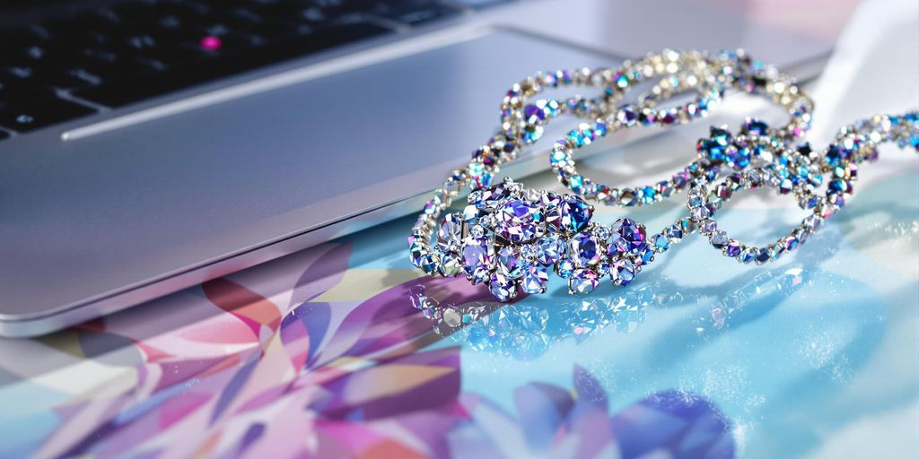 Bijoux étincelants posés près d'un ordinateur portable sur fond neutre
