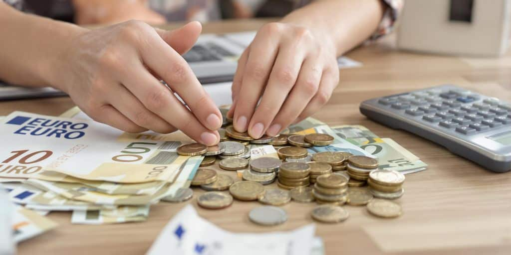 Personne compte des pièces et billets sur une table.