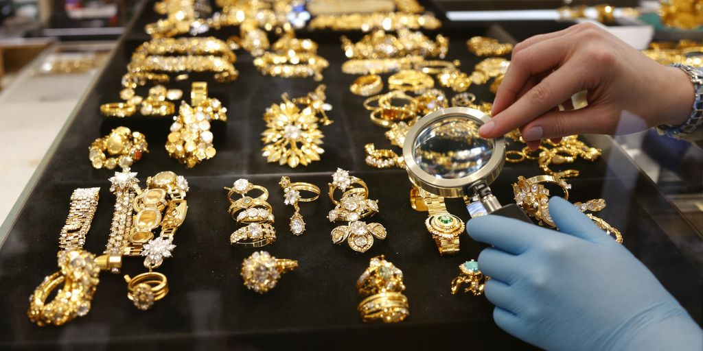 Un bijoutier examine des bijoux en or sur un comptoir.