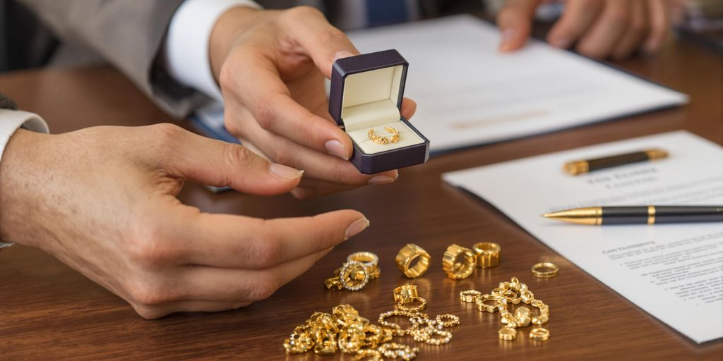 Deux mains échangent des bijoux en or sur une table.