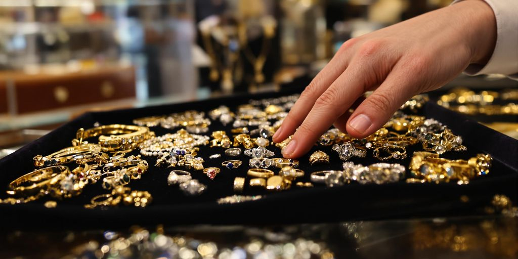 Main posant de vieux bijoux sur un plateau en velours.