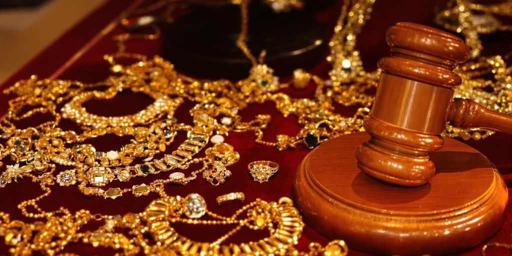 Bijoux en or et marteau de commissaire-priseur sur table.