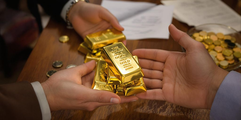 Deux mains échangent des lingots d'or sur une table.