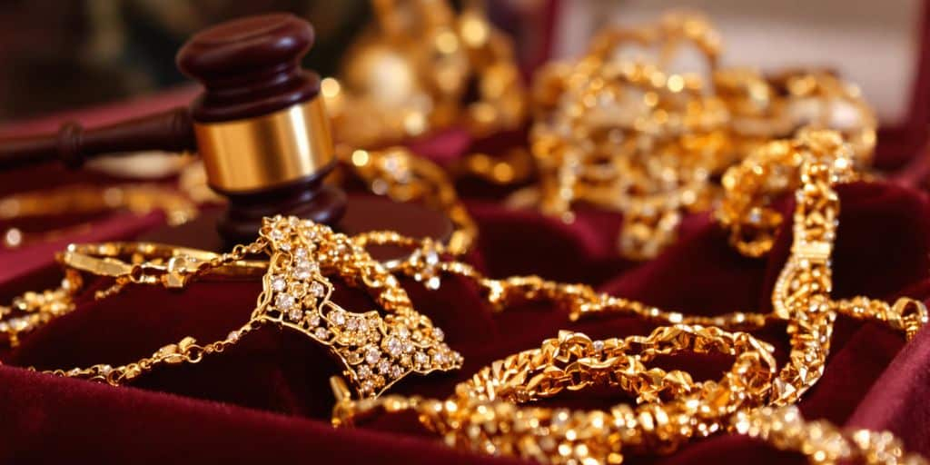 Bijoux en or sur une table d’enchères avec un marteau.