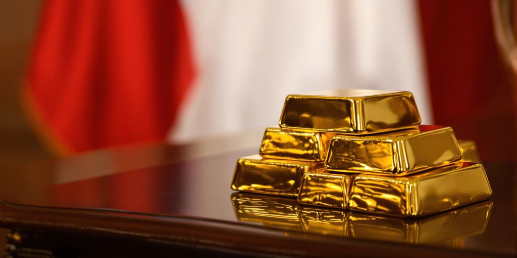 Lingots d’or sur une table avec drapeau français en arrière-plan.