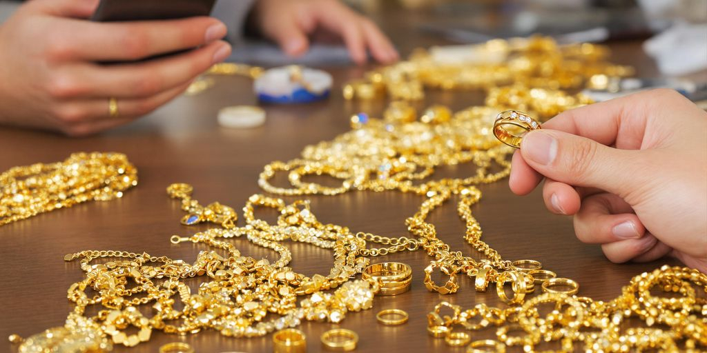 Bijoux en or sur une table avec main et smartphone