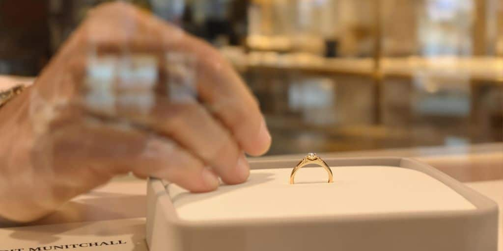 Main déposant une bague en or sur un plateau velours.