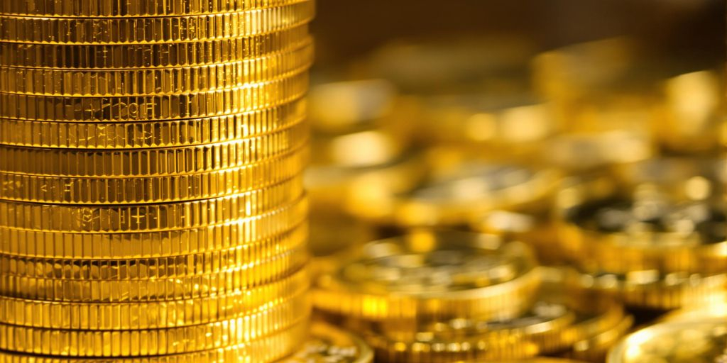 Pile de pièces d'or avec des bitcoins en fond.