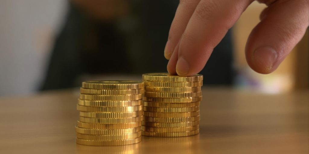 Main tendue vers des pièces d’or sur une table