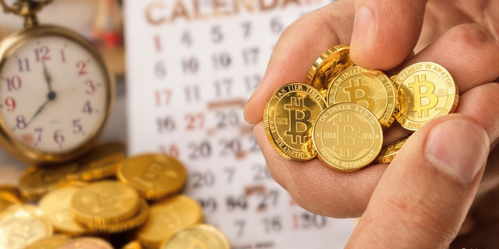 Main tenant des pièces d’or devant une montre et un calendrier