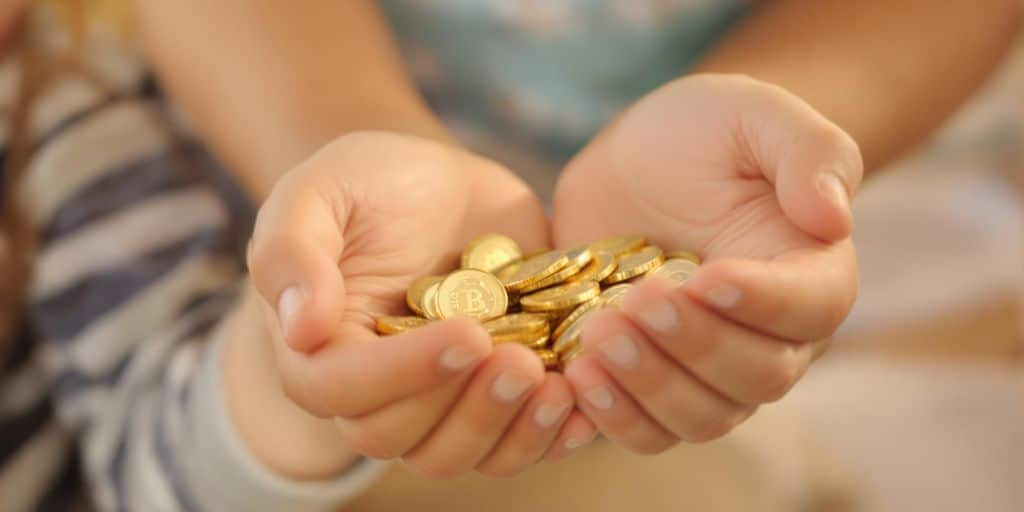 Enfant tenant des pièces d'or avec un parent à côté.