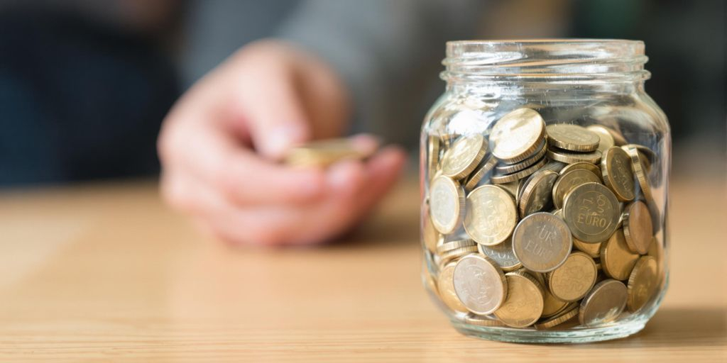 Bocal de pièces en euros sur une table en bois.