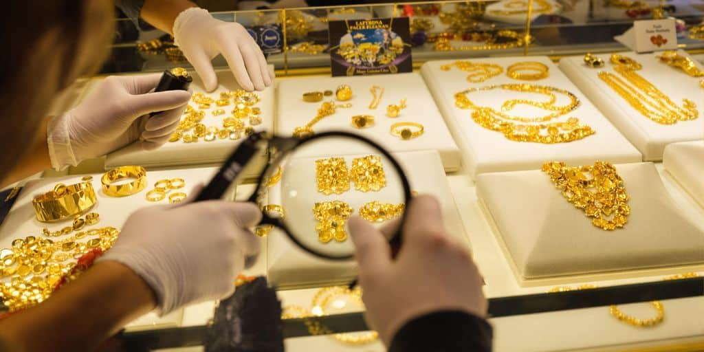 Personnes inspectant des bijoux en or sur un comptoir vitré