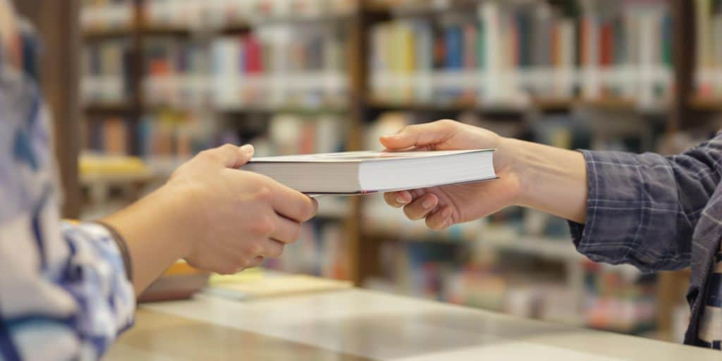 Personne rendant un livre à un comptoir de bibliothèque.