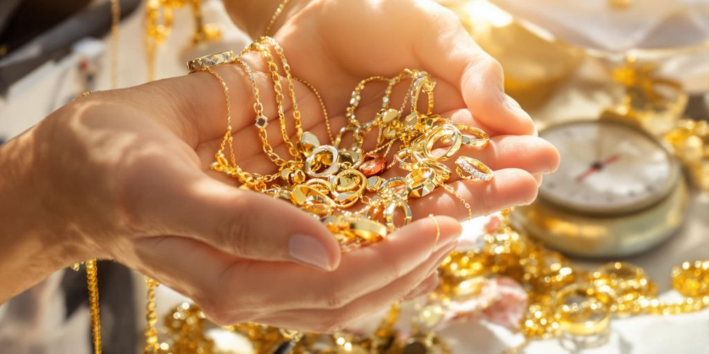 Mains tenant des bijoux en or près d’une balance de bijoutier