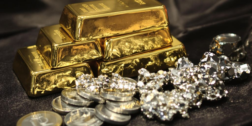 Lingots d’or et pièces d’argent sur une surface sombre.