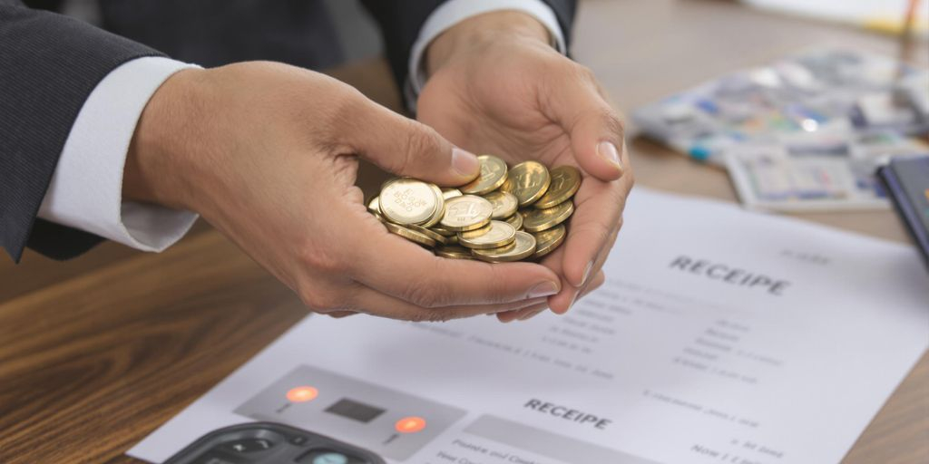 Main tenant des pièces d'or et reçu sur une table.
