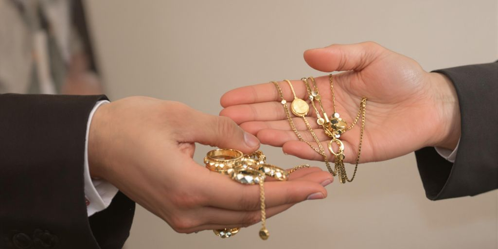 Deux mains échangent des bijoux en or en gros plan.