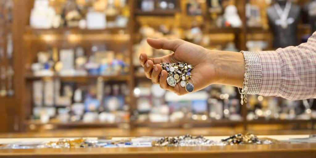 Main tendant des bijoux au comptoir d'un bureau de prêt