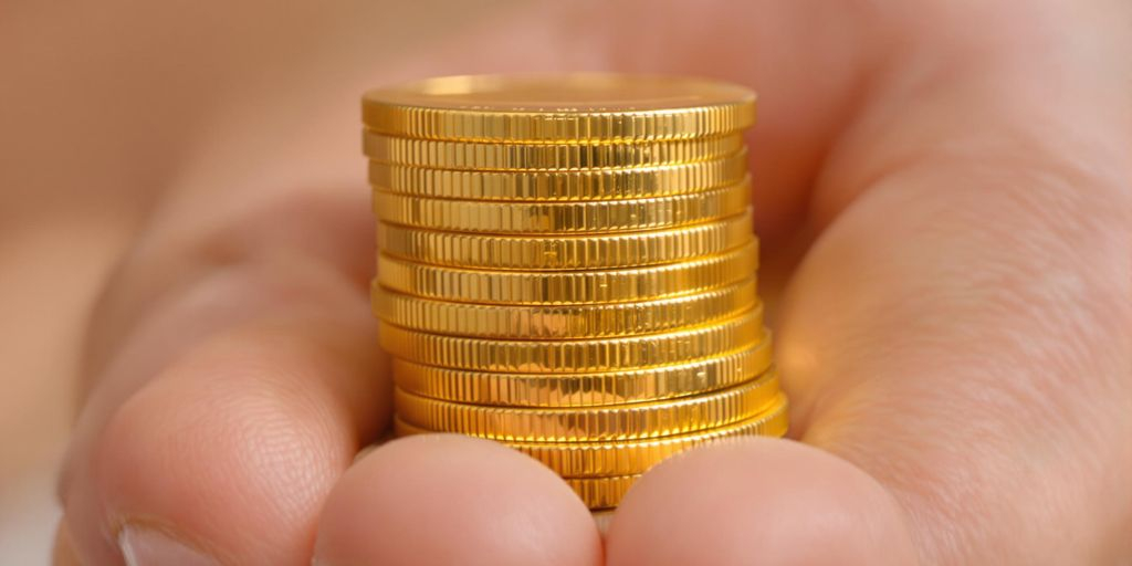 Une main tenant un tas de pièces d'or brillantes.
