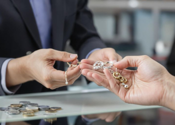 Main qui remet bijoux à un agent derrière un comptoir