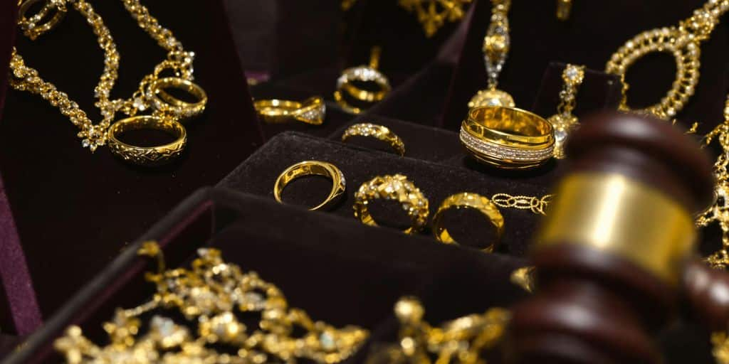 Bijoux en or et marteau de commissaire-priseur sur plateau.