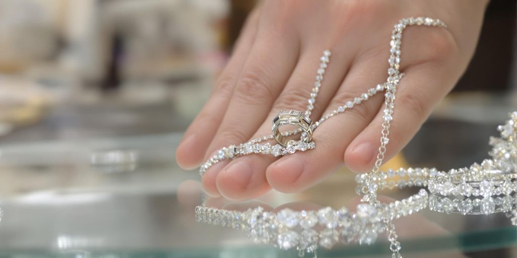 Main argent tenant bijoux en argent et platine sur comptoir.