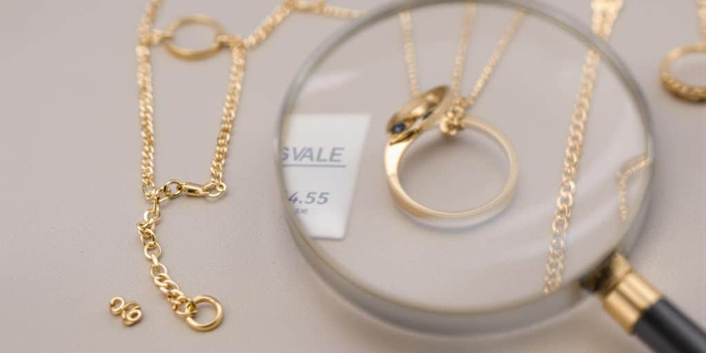 Bijoux en or avec loupe, détail du poinçon visible.