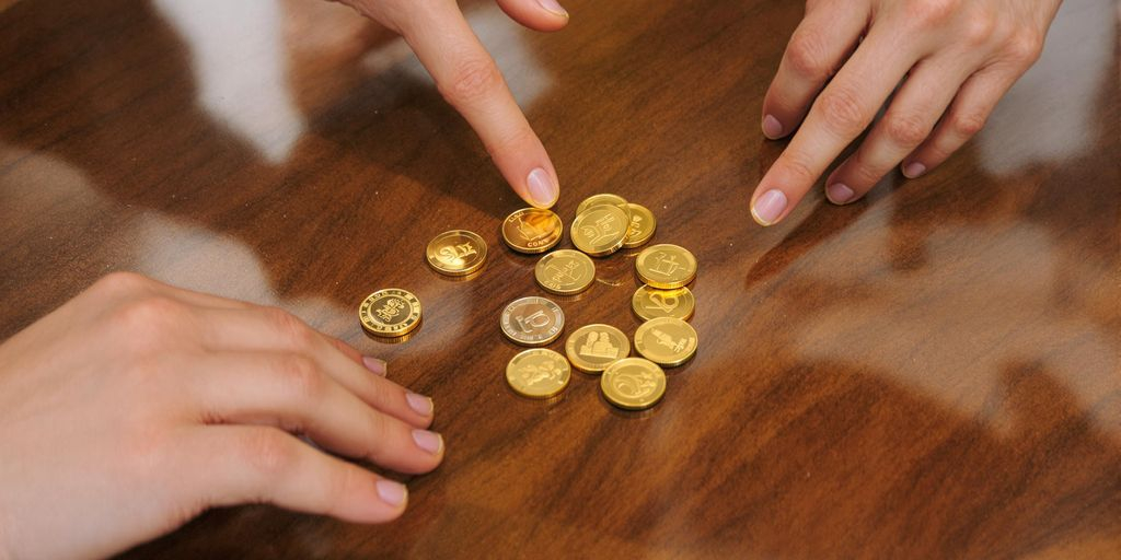 Plusieurs mains prennent des pièces d'or sur une table.