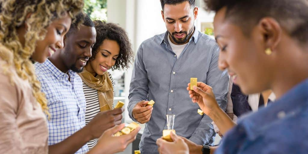 Jeunes tenant des pièces et lingots d’or autour d’une table.