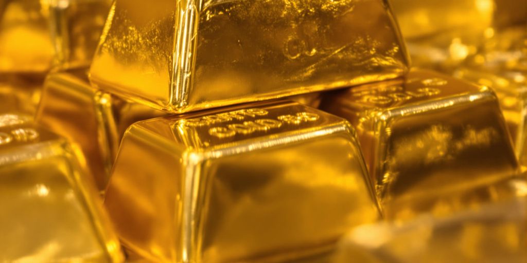 Lingots d'or brillants empilés sur une surface sombre.
