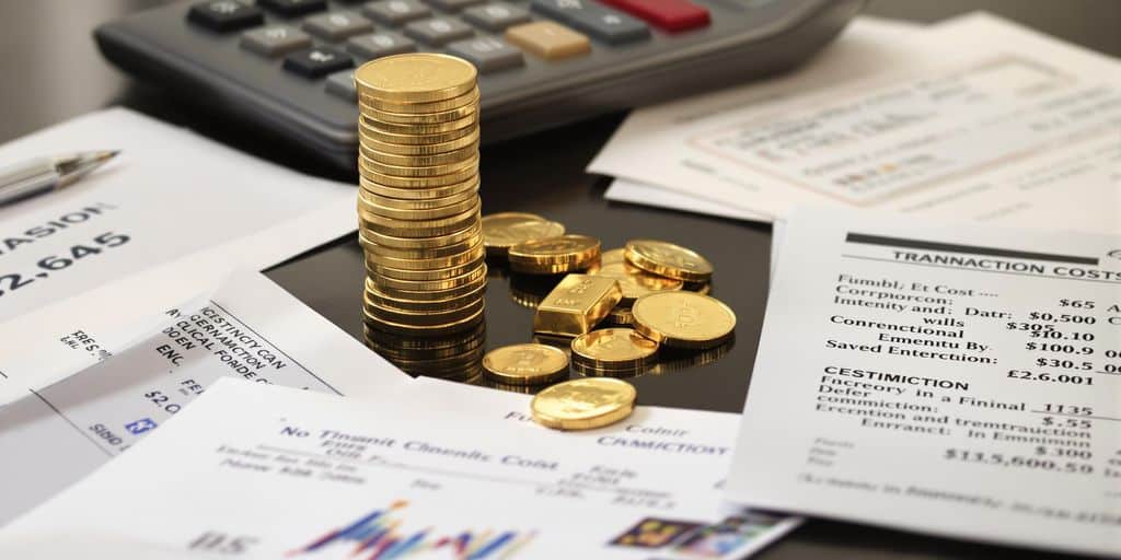 Pièces d'or et lingots empilés, entourés de documents.